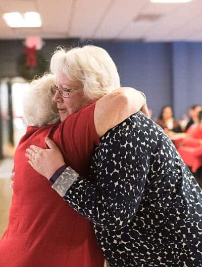 Two older women greeting each other with a hug